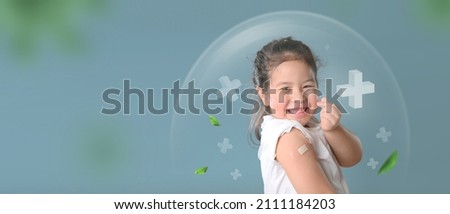 Coronavirus Vaccination Advertisement. Happy Vaccinated Little asian girl Showing Arm With Plaster Bandage After Covid-19 Vaccine Injection Posing Over Blue Background, Smiling To Camera. Royalty-Free Stock Photo #2111184203