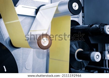 Fragment of the conveyor of sticking labeling machine. Abstract industrial background. Royalty-Free Stock Photo #2111192966
