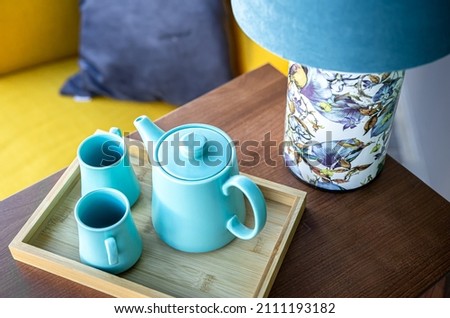 Teapot and two blue cups on the table, top view.