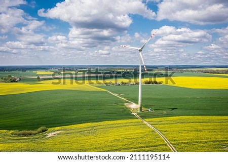 Stunning yellow rape fields and wind turbine. Poland agriculture. Aerial view of nature at spring in Europe.