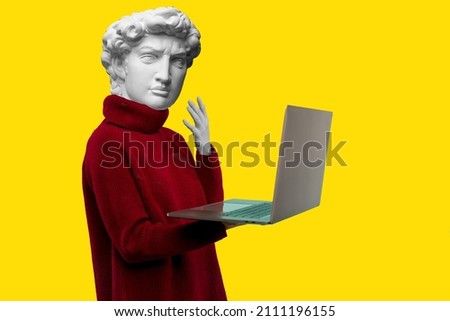 Abstract modern collage. The man with the plaster head of David in a red sweater looks at a laptop screen on a yellow background Royalty-Free Stock Photo #2111196155