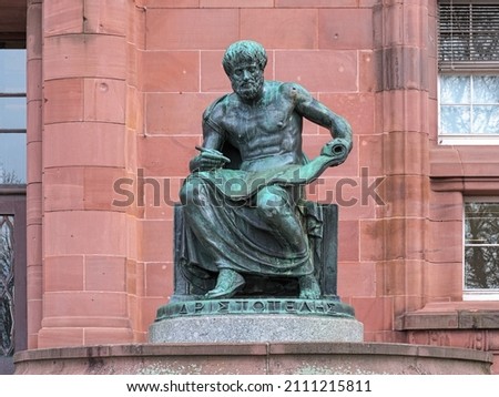Freiburg im Breisgau, Germany. Aristotle Statue in front of the main building of Freiburg University. The statue was erected in 1921. Greek text on plinth means Aristotle. Royalty-Free Stock Photo #2111215811