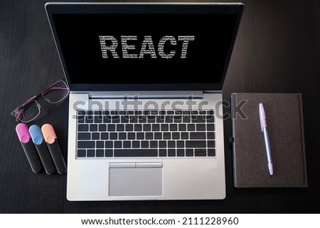 Top view of laptop with text React. React inscription on laptop screen and keyboard. Learn react language, computer courses, training.  Royalty-Free Stock Photo #2111228960