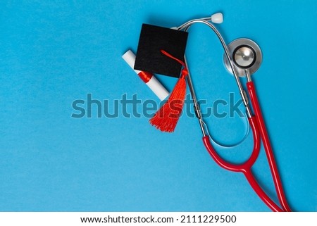 graduation medical concetp. Graduation cap, diploma and stethoscope on blue background Royalty-Free Stock Photo #2111229500