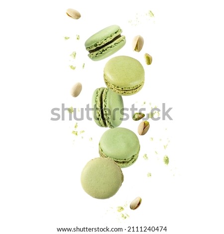 Flying green sweet pistachio macarons macaroons with crumbs and nuts isolated on white background Royalty-Free Stock Photo #2111240474