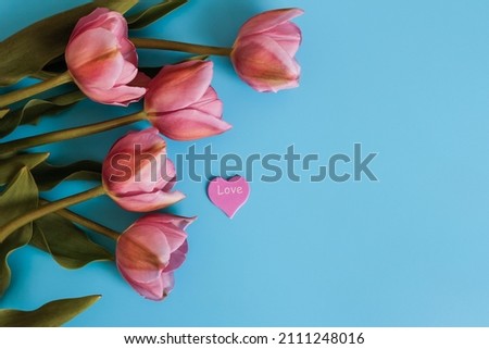 Tulip bouquet flowers and heart with text Love on blue background. valentine's day background with copy space