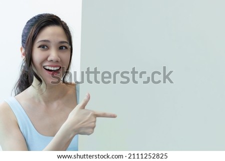 Asian beautiful woman are pointing to space area and light green signboard for a present a text and promotion with smiling and happiness and proud to present. Royalty-Free Stock Photo #2111252825