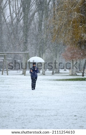 Candamia park snowy day in winter girl walking with her photo camera and holding an umbrella, Leon Spain