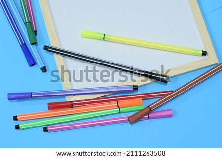 Selective Focus of A Multicolour Magic Ink Pens On A Wooden White Board, Isolated With Blue Background 