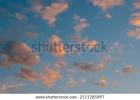 relaxing sunrise cloudscape sky with pink black and white coloured cumulus cloud formation in a pastel blue sky. Sunset or sunrise background image