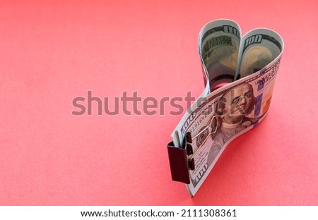 Heart made of dollar bills on a red background.