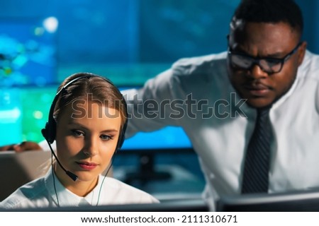 Aircraft flight control officer monitors the approach of aircraft from control tower. Air services office is equipped with navigation systems, radars and computer stations. Aviation concept. Royalty-Free Stock Photo #2111310671