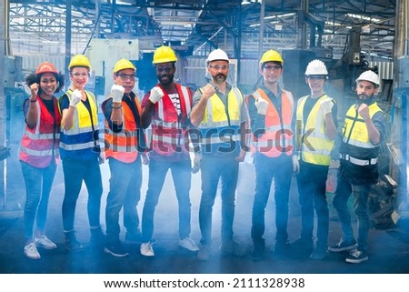 Workers and workers are standing in the factory. Group Staff Standing In Engineering Factory.