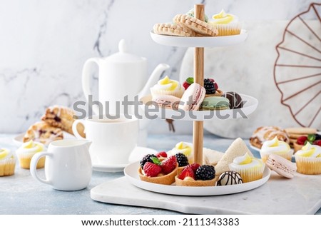 Spring or summer dessert table, three tiered tray with variety of desserts and sandwiches for tea Royalty-Free Stock Photo #2111343383