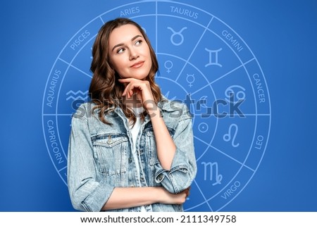Pensive young woman on the background of the zodiac circle, astrology. Blue background. Predictions, divination Royalty-Free Stock Photo #2111349758