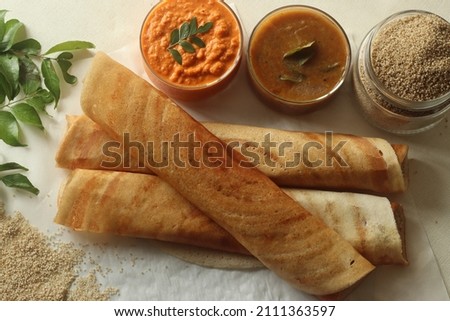 Crispy crepes made of little millets and lentils. Commonly known as little millet dosa. Plated as dosa rolls. Served with coconut spicy condiments and sambar. Shot on white background Royalty-Free Stock Photo #2111363597