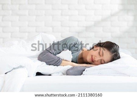 Beautiful Attractive Asian woman sleep and sweet dream lying on bed in cozy bedroom in the morning feeling so relax and comfortable.Healthy Young female sleep with bedtime at home.Healthcare Concept Royalty-Free Stock Photo #2111380160