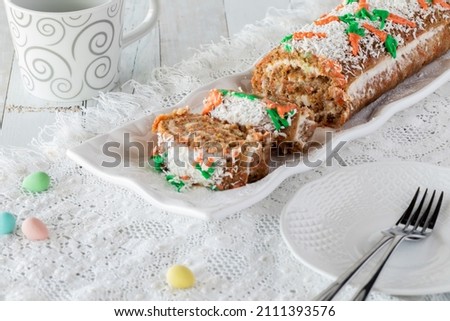 A platter of carrot cake jelly roll sliced into with plates for serving.