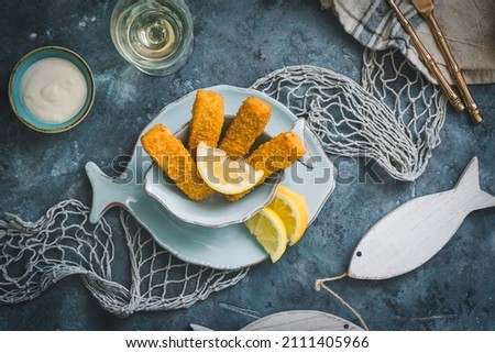 Fish fingers with lemon and nautical decoration on a blue background, top view