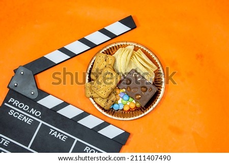 clapper board of video cinema in studio.Movie production clapper board, slate film. Video live streaming chocolate candy and bars with candy on orange background