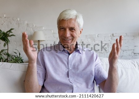 Happy senior 70s man talking and smiling at camera on video call, making hand gestures, laughing, having virtual conversation, speaking on online conference. Elder person head shot hope portrait