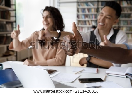 Audience of happy satisfied students thanking teacher, speaker for seminar, lesson, class in library, showing like thumb up gesture, smiling, expressing approval, positive feedback. Close up of hand