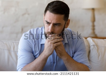 Worried concerned millennial business man thinking over bad news, problem solving, feeling stressed, depressed, frustrated, coping with nervous breakdown, emotional crisis. Negative emotions concept Royalty-Free Stock Photo #2111421131