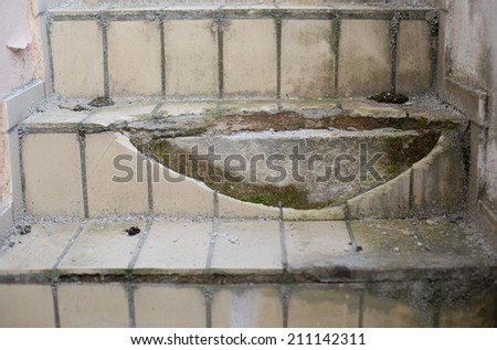 An old staircase with broken tiles Royalty-Free Stock Photo #211142311