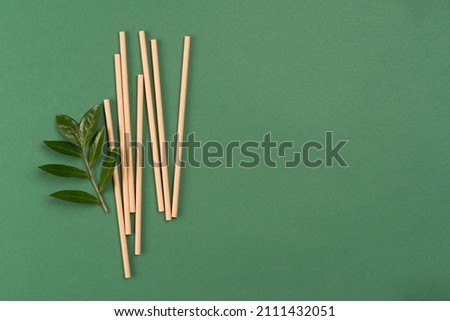Banner with mockup image of kraft paper drinking straws on green background with copy space and green fresh leaves around. Sustainable lifestyle and zero waste concept. Ethical consumerism. Flat lay Royalty-Free Stock Photo #2111432051