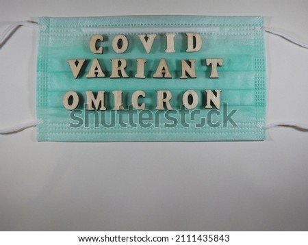 The word covid variant omicron in wooden letters on the face mask. High quality photo