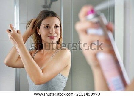 Beautiful young woman applying dry shampoo on her hair. Fast and easy way to keep hair clean with dry shampoo. Royalty-Free Stock Photo #2111450990