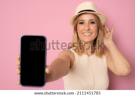 Close up portrait of young woman in straw hat showing blank screen smartphone isolated over pink background