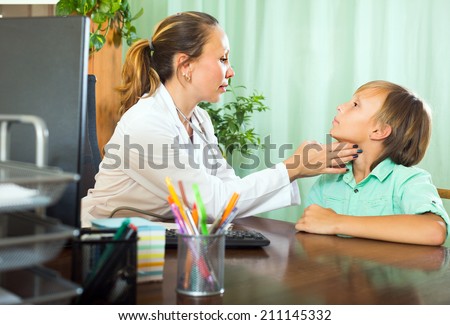 Female doctor checking thyroid of teenage boy patient in clinic 