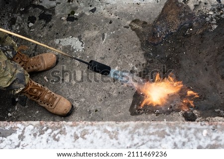 Downpipe repair. Heating the gutter area with a gas burner during repair of downpipe Royalty-Free Stock Photo #2111469236