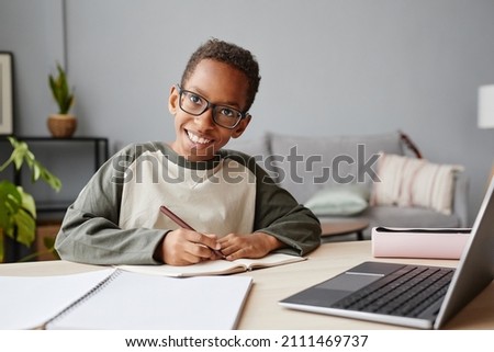 Portrait of smiling African-American boy wearing glasses while studying at home, homeschooling concept, copy space Royalty-Free Stock Photo #2111469737