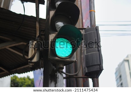 green traffic light with blurred background in a crosswalk. Traffic control and regulation concept