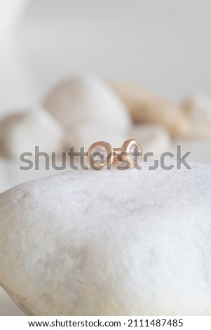 Close up picture of gold plated earrings with natural lighting on a blurry background