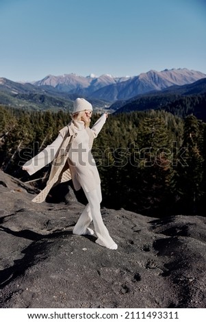 woman in autumn clothes stands on a rock blue sky lifestyle
