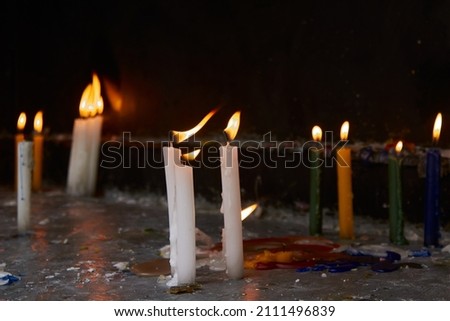 Photograph a set of lit candles of various colors with a black background