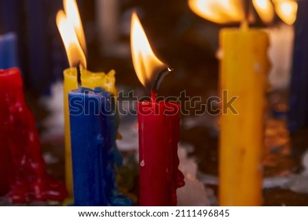 Photograph a set of lit candles of various colors with a black background