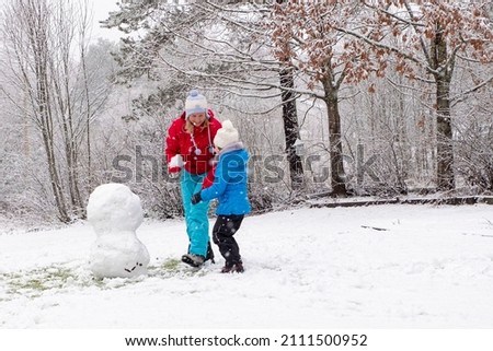 Snowball game. A young woman and a 5-year-old child make a snowman. Fun and happiness with family.