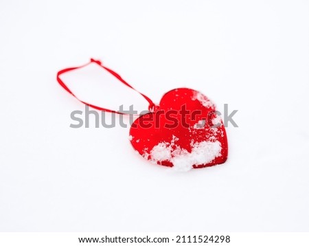 Beautiful glassy red heart in the snow. In a snow winter background. The 14th of February. Saint Valentine's Day.  Love and St. Valentine day concept. Frozen heart. Red on white