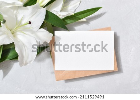 The template is a blank paper and an envelope with space for text on a gray background with lily flowers. Flat top view, a place to copy.