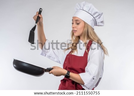 Chef cook woman. Cook with frying pan in hand. Chef girl on light background. Young woman works as chef in restaurant. Cook student is engaged in cooking. She is studying to be pastry chef concept Royalty-Free Stock Photo #2111550755