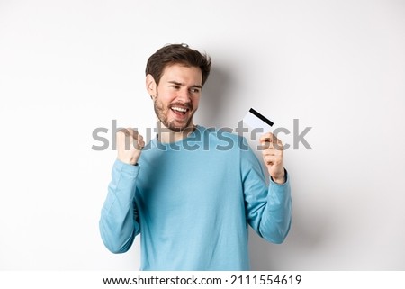 Happy man dancing with plastic credit card, smiling and saying yes, celebrating on white background