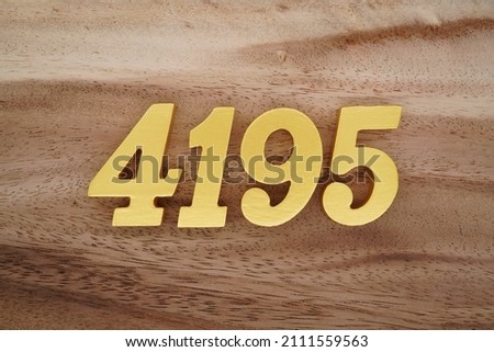 Wooden Arabic numerals 4195 painted in gold on a dark brown and white patterned plank background.