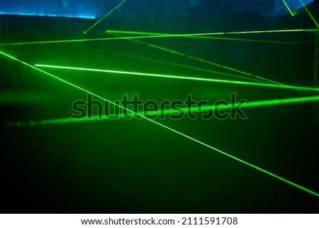 Bright green neon laser lights illuminate the darkness creating lines and triangle shapes in sci-fi effect.
