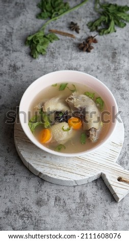 chicken soup in a bowl on cutting board. Grey background 