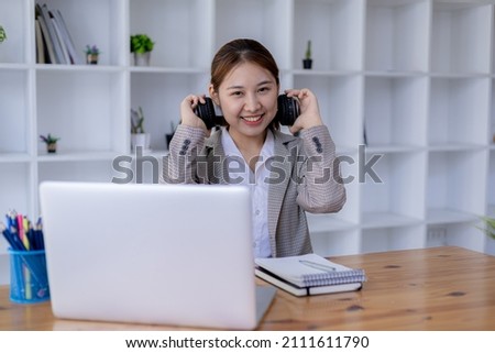 Beautiful Asian woman holding headphones around her neck, she is a student, she is studying online. The concept of online learning due to the COVID-19 outbreak to prevent an outbreak in the classroom.