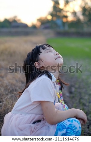Asian child girl is sitting in the field. 